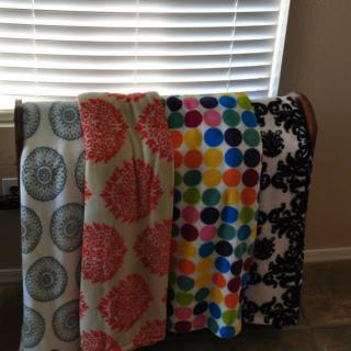 A collection of colorful patterned blankets displayed in a home setting.