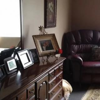 A cozy living room with a dresser displaying photo frames and a comfortable leather sofa.