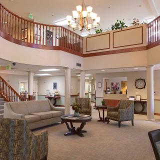 A spacious lobby with elegant furnishings, a chandelier, and a staircase leading to an upper level.