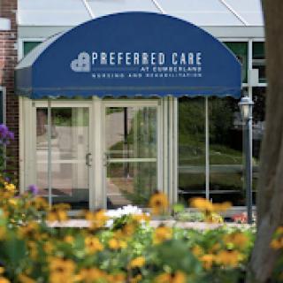 Entrance of Preferred Care facility surrounded by blooming flowers.