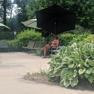 A person enjoying a peaceful moment in a park under an umbrella.