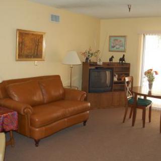 A cozy living room with a leather sofa, television, and a small dining table.