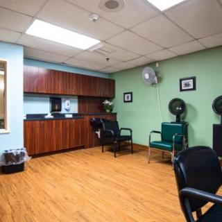 A cozy salon interior with chairs and hair dryers, featuring wooden flooring and cabinets.