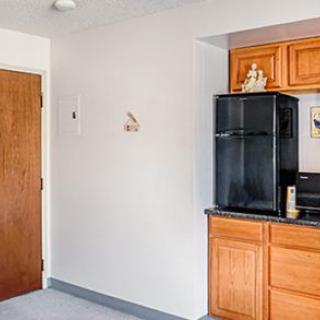 A kitchen area with wooden cabinets, a black refrigerator, and a microwave.