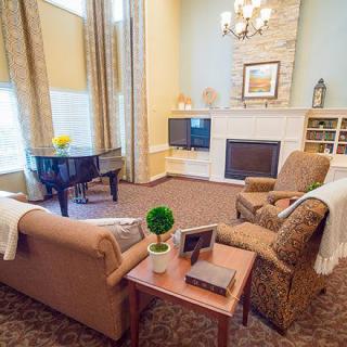 A cozy living room featuring a fireplace, comfortable seating, and a grand piano.
