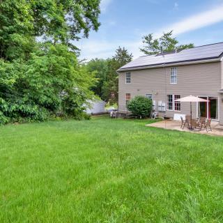 A spacious backyard with a well-maintained lawn and patio area next to a two-story house.