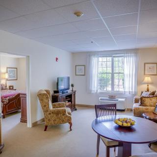 A cozy living space with a view into the bedroom, featuring comfortable furniture and natural light.