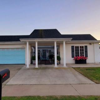 A suburban house with a blue garage door and white columns at sunset.