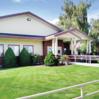 A well-maintained building with a manicured lawn and trees on a sunny day.