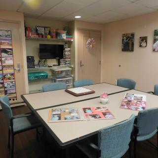 A cozy waiting room with a table, chairs, and magazines for guests.