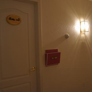 A dimly lit hallway with a closed door and a wall-mounted light fixture.