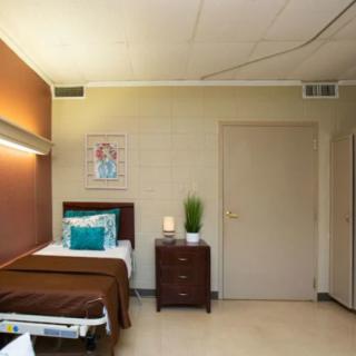 A simple and clean hospital room with a single bed and nightstand.