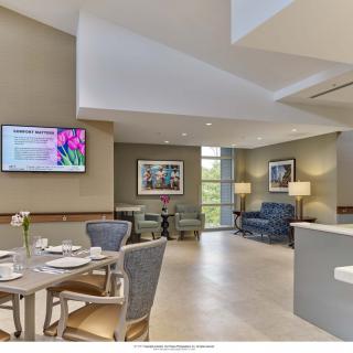 A modern lounge area with comfortable seating, a dining table, and wall-mounted television.