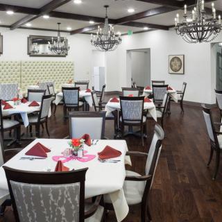An elegant dining room with neatly arranged tables and chandeliers.