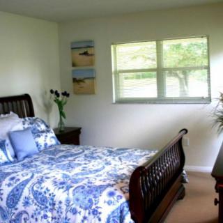 A cozy bedroom with a wooden bed, blue and white bedding, and natural light from a window.