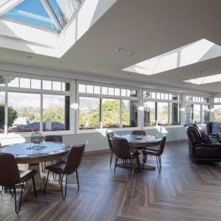 A spacious dining and living area with large windows and skylights flooding the room with natural light.
