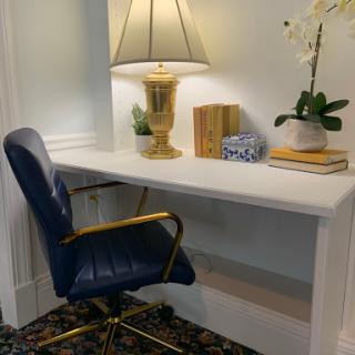 A cozy workspace featuring a sleek desk, comfortable chair, and a touch of greenery.