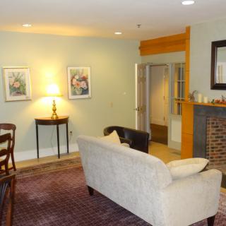 A cozy living room featuring a sofa, artwork on the walls, and a fireplace.