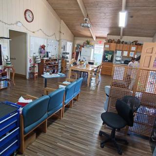 An office interior with a waiting area featuring chairs, desks, and a wooden floor.