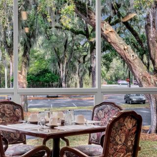 A cozy dining area with a view of lush outdoor trees through large windows.