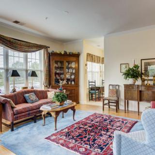 A traditional living room with comfortable seating, a patterned rug, and a display cabinet.