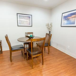 A cozy dining room featuring a wooden table surrounded by chairs, complemented by wall art and elegant flooring.