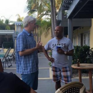 Two men having a conversation on a patio during the daytime.
