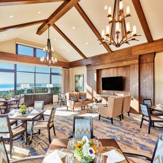 A luxurious dining room with large windows, elegant chandeliers, and comfortable seating.