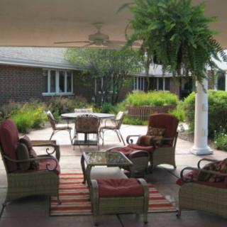 A cozy outdoor patio with comfortable seating surrounded by lush greenery.