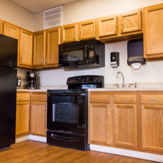 A modern kitchen featuring wooden cabinets and black appliances.