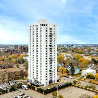 A tall white residential building stands prominently against an urban backdrop.