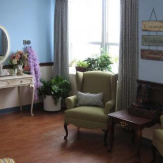 A cozy living room with an armchair, vanity table, and indoor plants by the window.