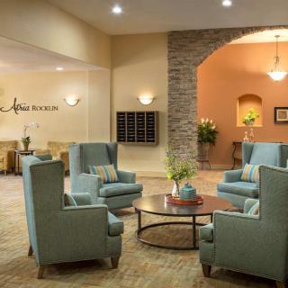 A cozy lobby area featuring blue armchairs and a circular coffee table.