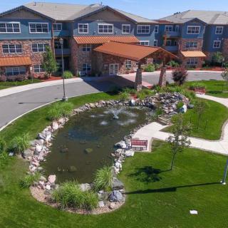 A scenic view of a building entrance surrounded by a landscaped garden with a pond.