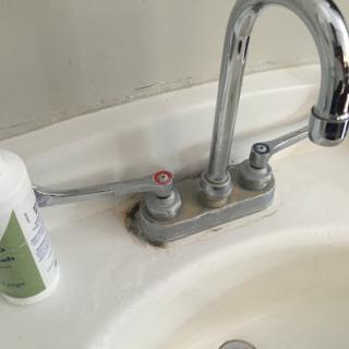 A close-up view of a bathroom sink with a chrome faucet and hygiene product.