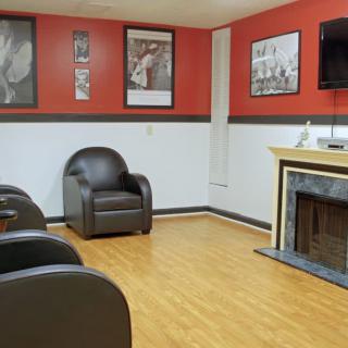 A modern waiting room with armchairs, a television, and a fireplace, featuring red and white walls.