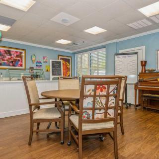 A cozy meeting room with a round table, chairs, and colorful artwork on blue walls.