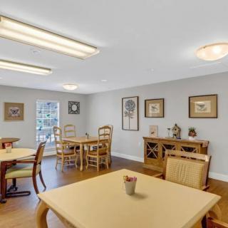 A bright and spacious dining area with neatly arranged tables and chairs, complemented by artwork on the walls.