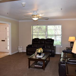 A cozy living room with leather sofas, a coffee table, and a ceiling fan.
