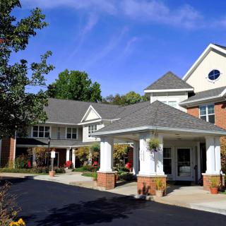 The image shows the exterior of a residential building with a covered entrance and well-maintained landscaping.