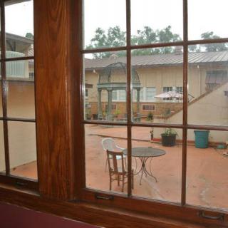 View of a courtyard through a window, featuring a table and chair on the patio.