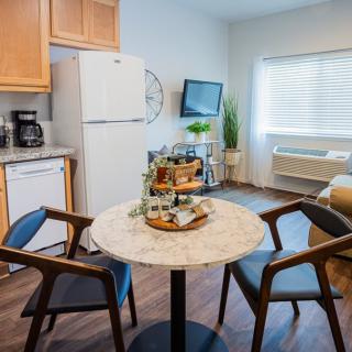 A cozy kitchen and dining area featuring a small round table with two chairs, modern appliances, and inviting decor.