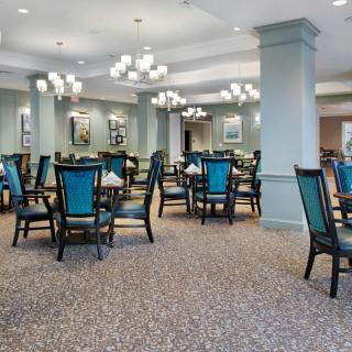 A spacious and elegantly designed dining room with multiple tables and chairs, featuring stylish lighting and decor.