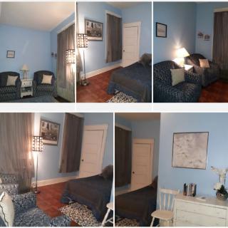 A cozy bedroom with blue walls, featuring a bed, chairs, and decorative items.