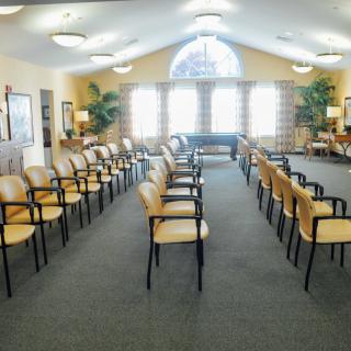 An empty waiting room with rows of chairs arranged neatly under soft lighting.
