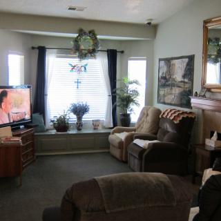 A cozy living room with comfortable seating, a television, and large windows letting in natural light.