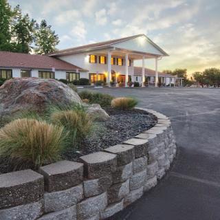 A welcoming hotel exterior during sunset, featuring a landscaped entrance and spacious parking.