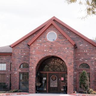 A brick building with a gabled roof and arched entrance.