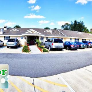 A building with a parking lot full of cars under a sunny, partially cloudy sky.