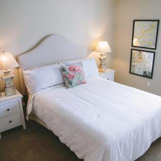 A cozy bedroom with a neatly made bed and elegant lamps.